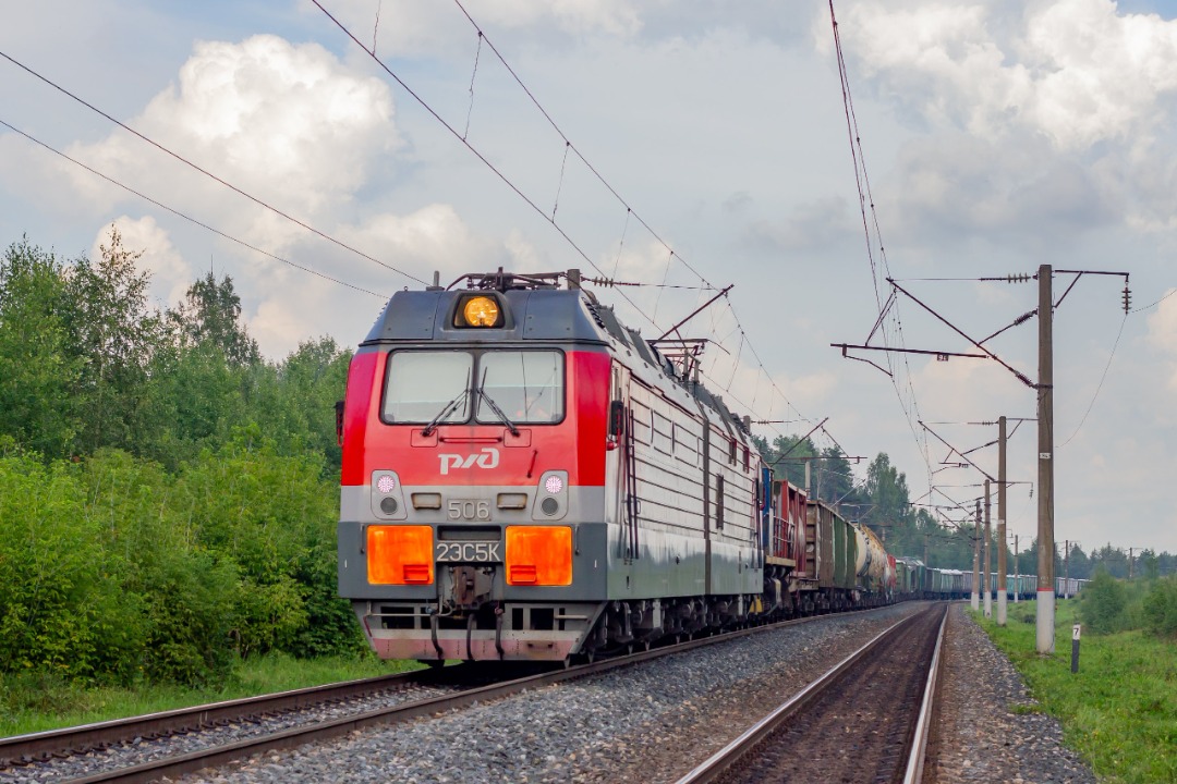 CHS200-011 on Train Siding: Electric freight locomotive 2ES5K-506 "Ermak" with a transportable diesel locomotive TEM2-879 and a freight train follows
the Bumkombinat -...