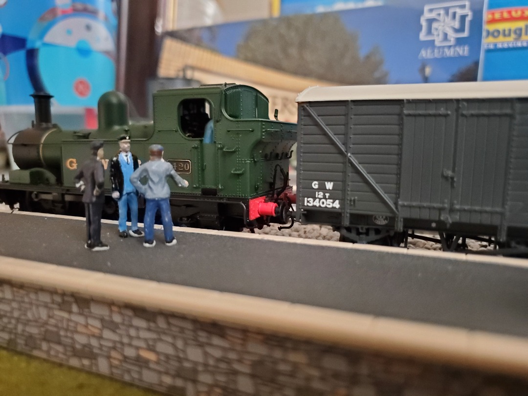 M. on Train Siding: GWR No. 1420 idles at a station platform while the station master argues with the guard about the unexpected arrival of the small goods
train.